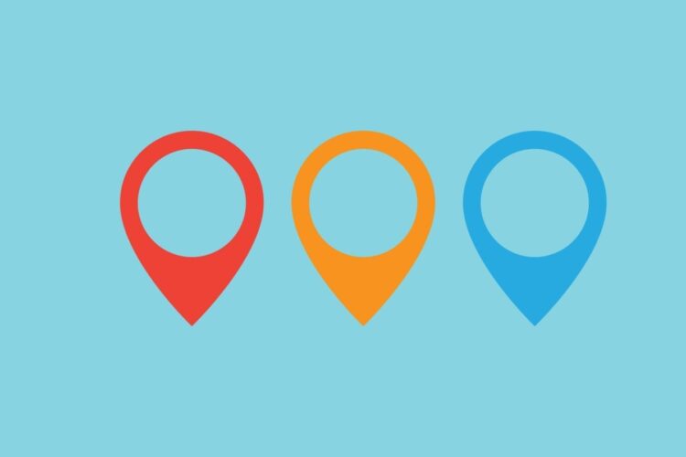 Three map location pin icons in red, yellow, and blue are arranged side by side on a light blue background.