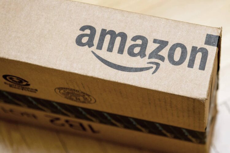 A cardboard shipping box with the Amazon logo printed on the side, placed on a wooden surface.