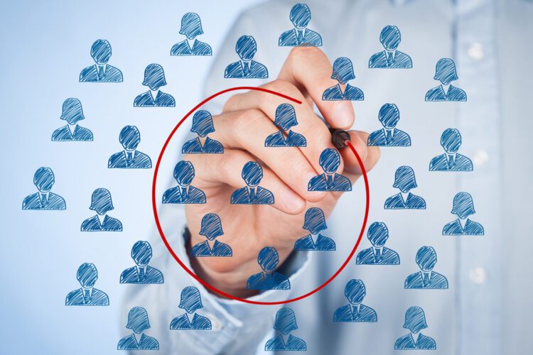 A person draws a red circle around a group of blue user icons on transparent screen, highlighting selected individuals among many.