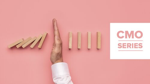 A hand stops falling wooden dominoes on a pink background, with the text "CMO SERIES" in a white box on the right.