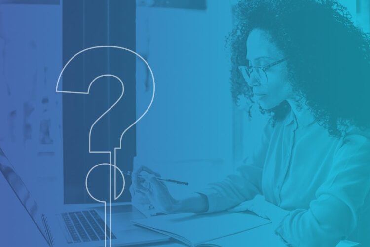 Woman with curly hair and glasses sits at a desk, writing in a notebook and looking at a laptop; a large, faint question mark overlays the image.