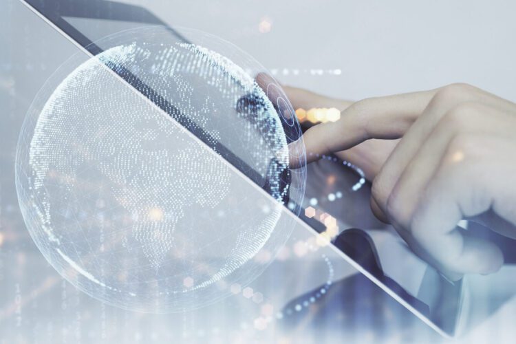 A hand touches a tablet screen with a digital globe and abstract network graphics overlaying the image, suggesting global connectivity and technology.