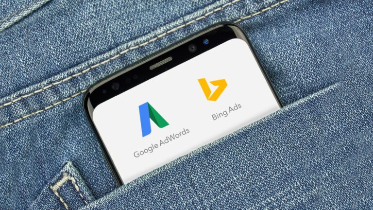 A smartphone in a denim pocket displays the Google AdWords and Bing Ads logos on its screen.