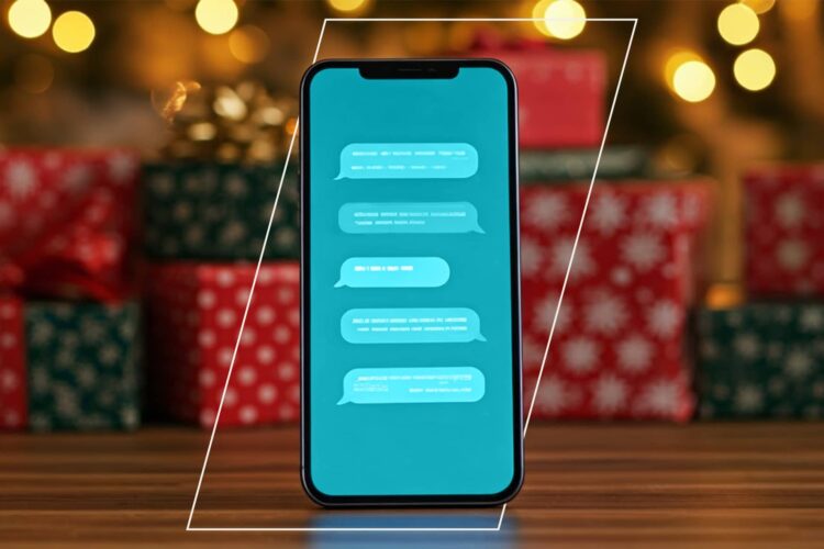 A smartphone displaying a chat conversation is placed upright on a wooden surface, with blurred gift boxes and holiday lights in the background.