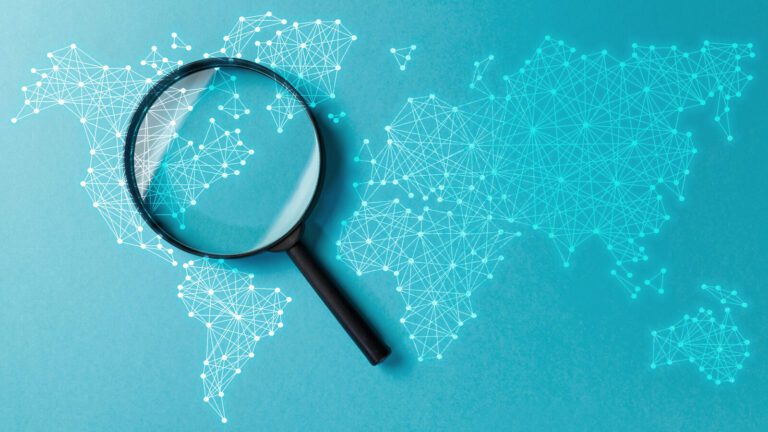 A magnifying glass placed over a blue digital world map with interconnected dots and lines, highlighting a section of the map.