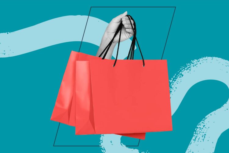 A hand holds two red shopping bags by their black handles against a teal background with abstract shapes.