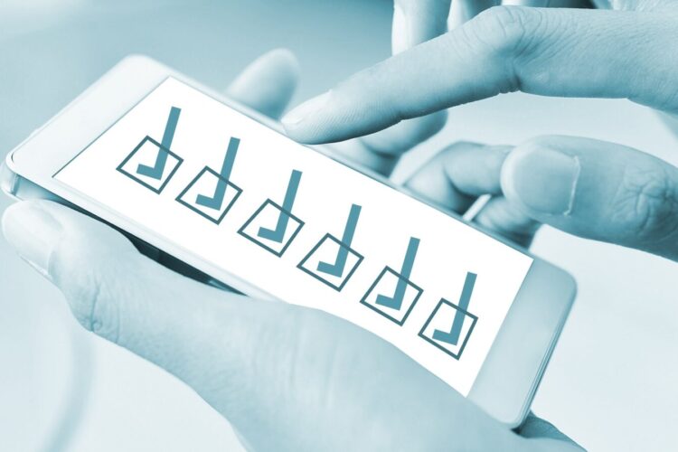 A person uses a smartphone displaying a survey or checklist with five checkboxes, all marked as completed.