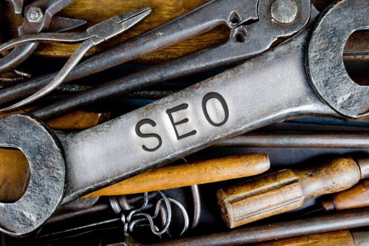 A large metal wrench labeled "SEO" lies on top of assorted hand tools, including pliers and screwdrivers.