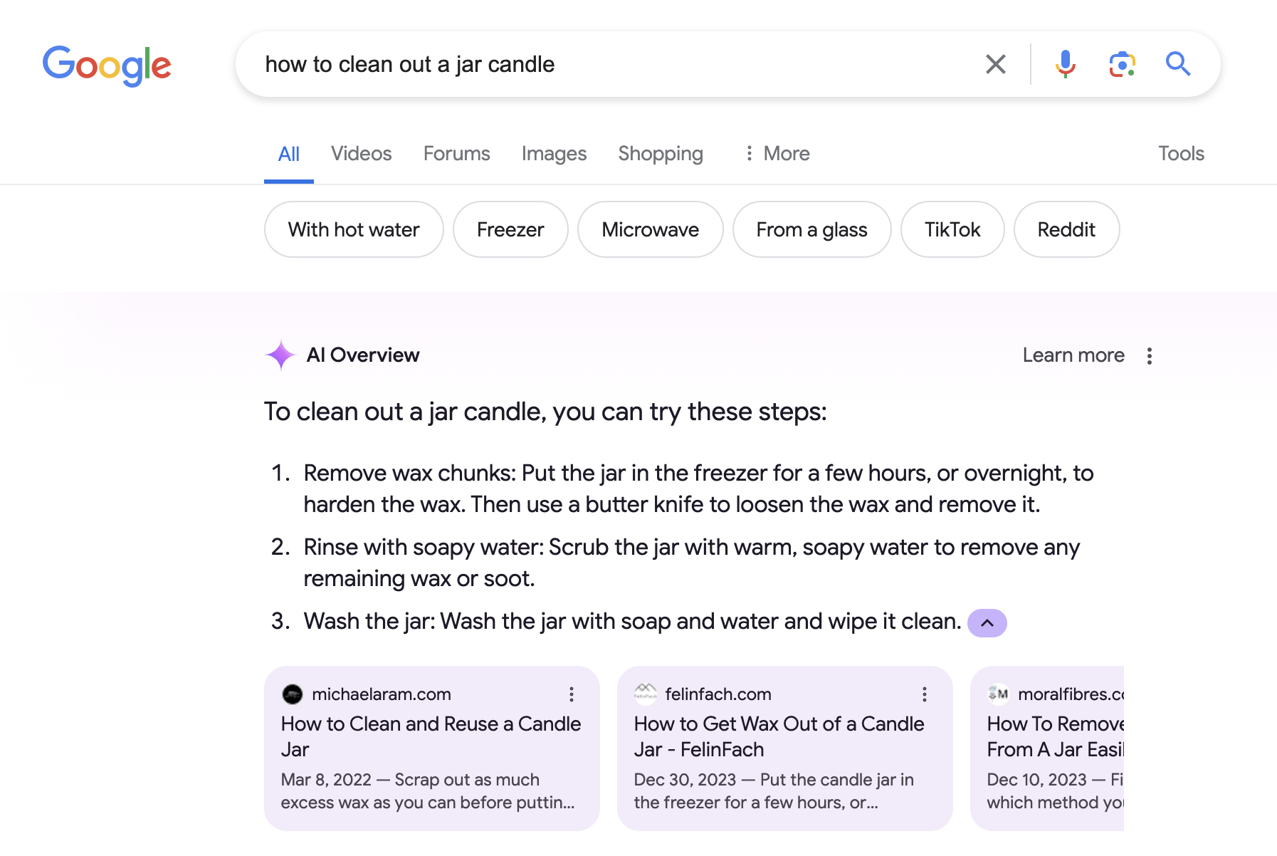 Screenshot of a Google search page showing an AI overview result at the top of the page. The result explains how to clean wax out of a jar candle and links related sources