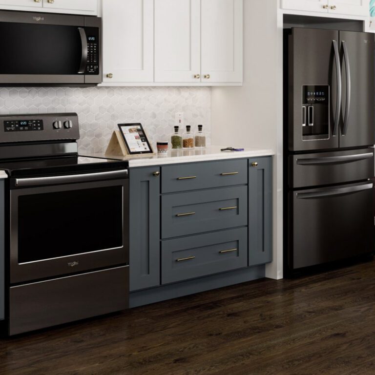 Modern kitchen with stainless steel appliances, blue and white cabinets, white hexagon tile backsplash, and dark wood floor.