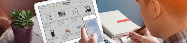 A person uses a smartphone and takes notes while viewing a laptop displaying a grid of product images; a potted plant and notebook are nearby.