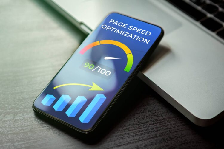 A smartphone displays a page speed optimization score of 90 out of 100, with graphical meter and chart, resting on a laptop keyboard.