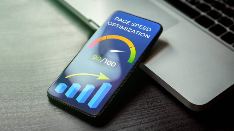 A smartphone displays a page speed optimization score of 90 out of 100, with graphical meter and chart, resting on a laptop keyboard.