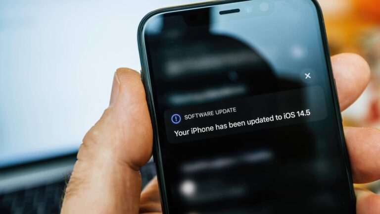 A hand holding an iPhone displaying a notification that the device has been updated to iOS 14.5.