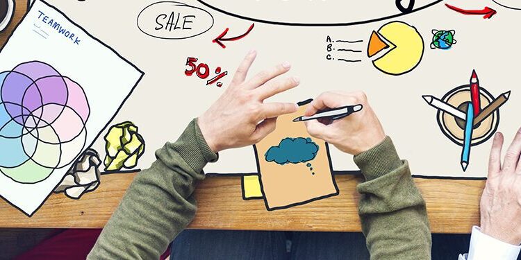 People sitting around a table working on creative projects, with drawings, color swatches, coffee cups, and stationery spread out.