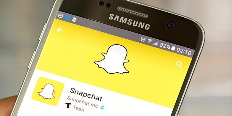 A Samsung smartphone displaying the Snapchat app page with the Snapchat ghost logo on the screen.