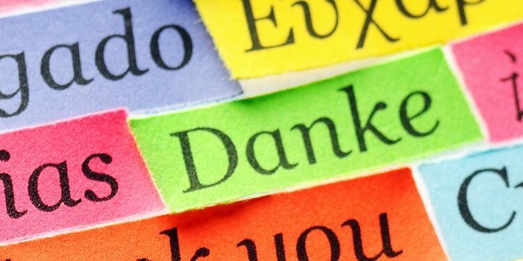 Colorful strips of paper display the word "thank you" in various languages, including Spanish, Portuguese, German, and others, arranged in overlapping rows.