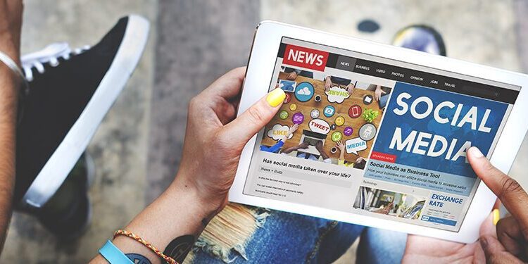 Two people using tablet devices; one screen displays a news website with a "Social Media" headline and various social media icons.