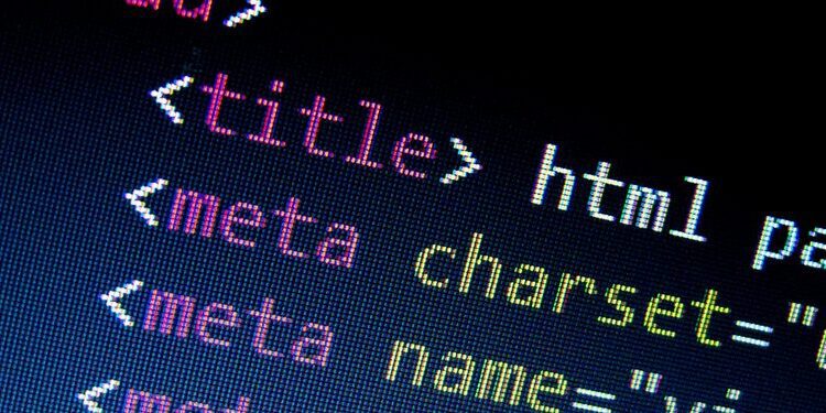 Close-up of a computer screen displaying HTML code with highlighted tags including title, meta charset, and meta name.