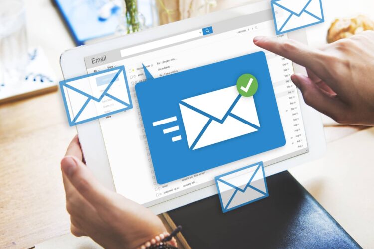 A person holds a tablet displaying an email inbox screen, with illustrated email icons and a checkmark symbol overlayed on the image.
