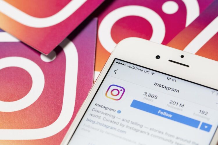 A smartphone displays the Instagram profile page, with Instagram logo cards in the background.