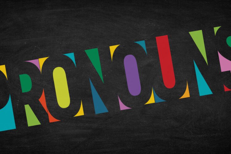 The word "PRONOUNS" in bold black letters with colorful shapes filling the interior, set against a chalkboard-like background.