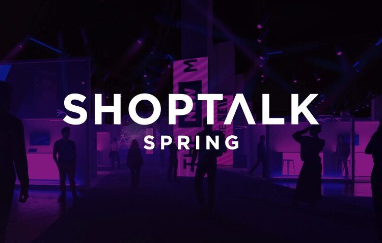 People walk in a dimly lit event space with purple lighting and the text “Shoptalk Spring” displayed prominently in the center.