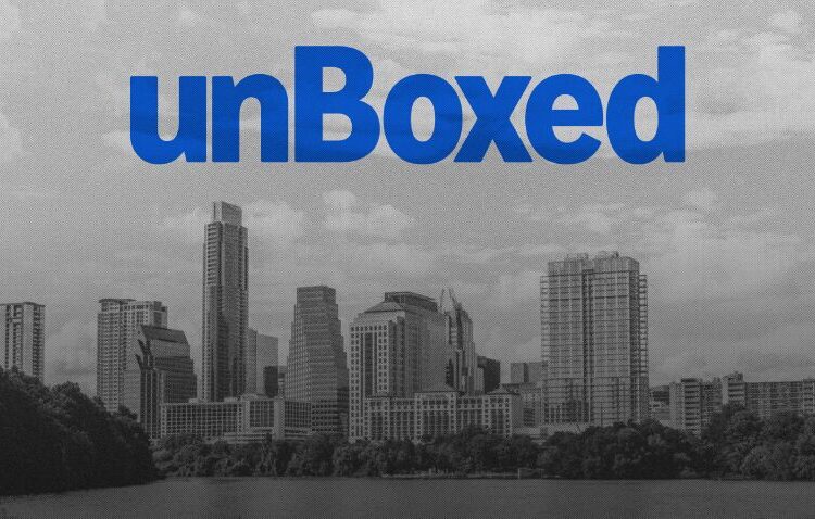 A grayscale city skyline with the word "unBoxed" in large blue letters centered at the top of the image.