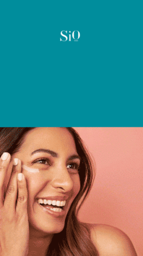 A woman smiling and applying cream to her face against a peach background, with the SiO logo displayed above on a teal background.