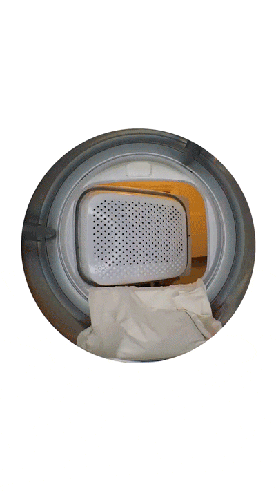 A close-up view inside a dryer shows a perforated metal panel and white laundry tumbling as the machine runs.