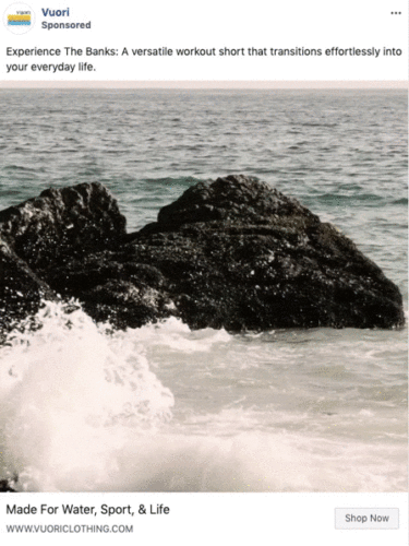 Waves crash against a large dark rock in the ocean under a cloudy sky, featured in a Vuori Clothing advertisement.