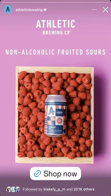 A can of Athletic Brewing Co. non-alcoholic fruited sour beer is displayed in a crate filled with fresh raspberries, with a "Shop now" button below.