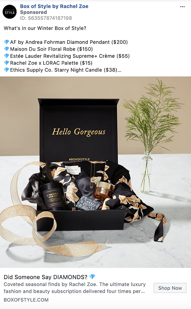 A black gift box with “Hello Gorgeous” inside, luxury beauty and fashion products, a gold floral robe, and a vase with greenery displayed on a marble surface.