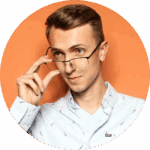 A person with short light brown hair wearing a light blue button-up shirt adjusts their glasses while looking slightly to the side against an orange background.