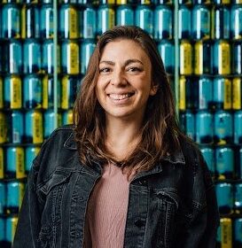 A woman smiling in front of a stack of cans.