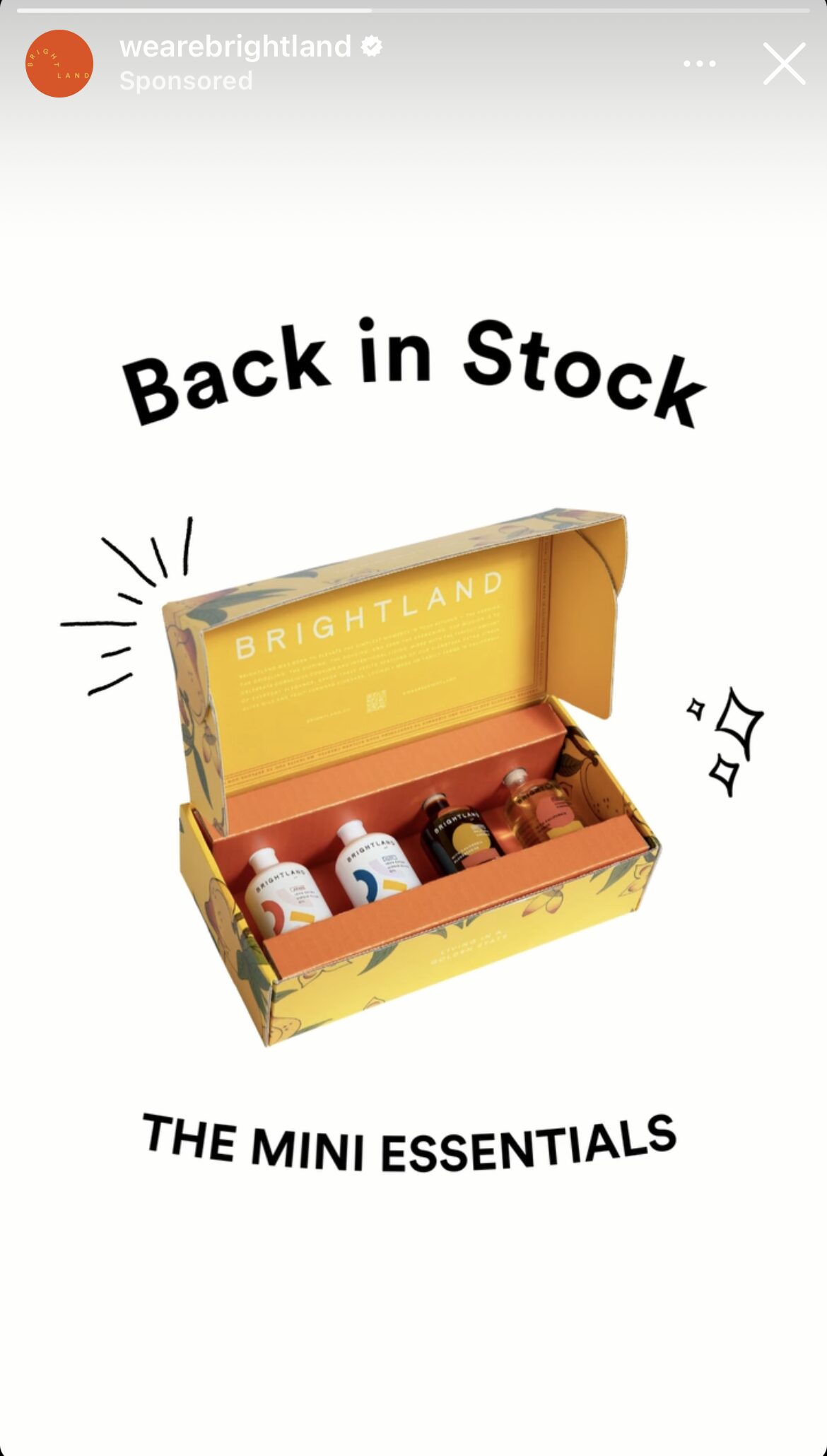 An open yellow Brightland box displaying four mini bottles, two white and two dark, labeled as "The Mini Essentials," with text stating "Back in Stock.