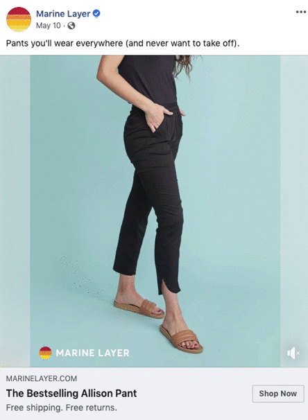 A woman stands against a light blue background wearing black ankle-length pants, a black top, and tan slide sandals.