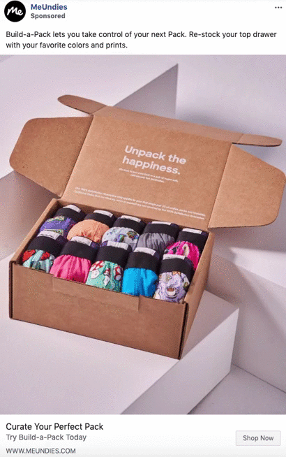 An open cardboard box contains neatly rolled pairs of colorful underwear, arranged in two rows, sitting on a white surface.