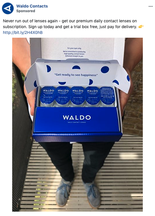 Person holding an open box containing five bottles of Waldo daily contact lenses with blue and white packaging.