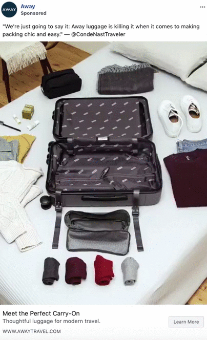 Open Away carry-on suitcase lies on a bed, surrounded by neatly folded clothes, shoes, and travel accessories, ready for packing.