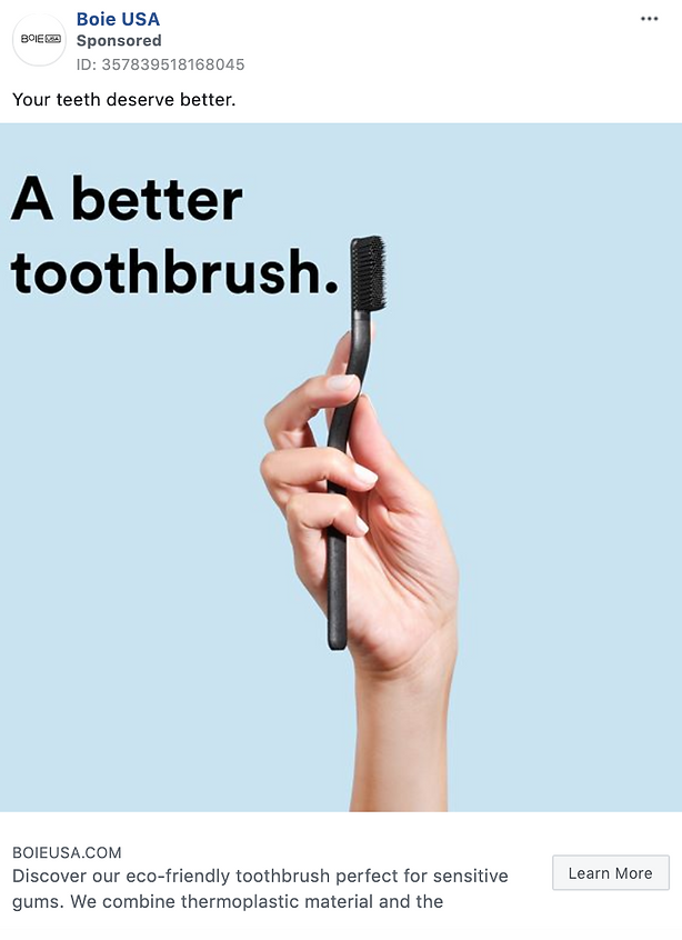 A hand holds a black toothbrush upright against a light blue background with the text "A better toothbrush." displayed beside it.