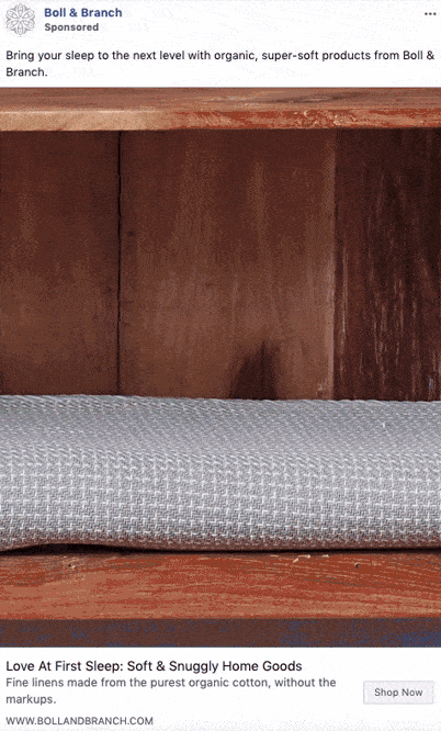 A folded gray textured blanket or sheet is placed neatly on a wooden shelf.