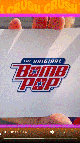 A hand holds a white card displaying "The Original Bomb Pop" logo in red and blue text with star designs.