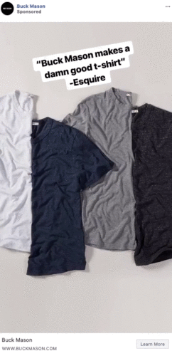 Four short-sleeve t-shirts in white, navy, gray, and charcoal are laid flat on a light surface. Text above reads: "'Buck Mason makes a damn good t-shirt' - Esquire.