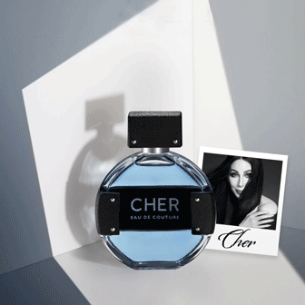 A round bottle of CHER Eau de Couture perfume sits next to a black-and-white photo of a woman with "Cher" written below it.