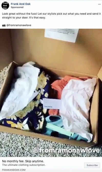 An open box containing assorted folded clothing items and a business card, placed on a surface.