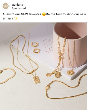 Gold necklaces, bracelets, and earrings are displayed on a cream-colored surface next to a pink mug and a white book.