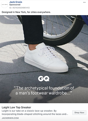 A close-up of a person wearing white low-top sneakers and light pants, standing beside a bicycle wheel. GQ and sneaker product info are overlaid on the image.