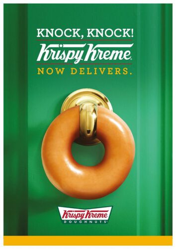 A Krispy Kreme doughnut hangs on a gold door knocker against a green door with the text, "Knock, Knock! Krispy Kreme Now Delivers.