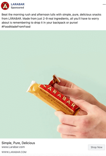 A hand is opening a LÄRABAR Peanut Butter Chocolate Chip snack bar against a light green background.